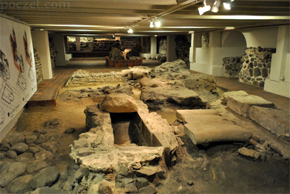 Fotografia przedstawia przedromańskie i romańskie pozostałości katedry w Gnieźnie, w postaci szeregu reliktów murów dawnych świątyń. Obiekty te zlokalizowane są w podziemiach obecnej katedry.
